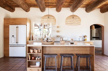 Modern kitchen island table in adobe-style inn with wicker pendant lights