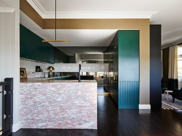 Art deco kitchen with pink stone island and green cabinets