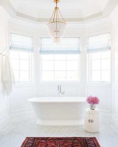 bathroom chandelier lighting idea with crystal and brass fixture hanging over tub
