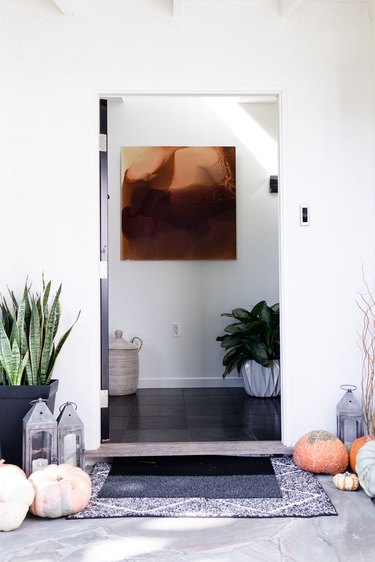 Minimalist entryway design with plants, artwork, pumpkins, lanterns, and art