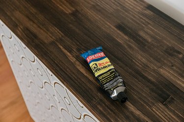 Use adhesive to attach the stained wood piece to the top of the cabinet.
