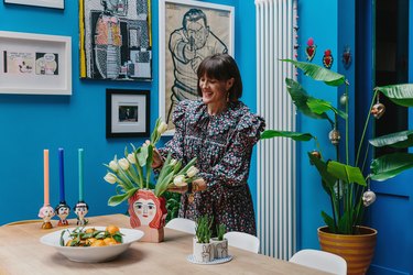 Zoe Anderson arranging tulips in her bright blue dining room