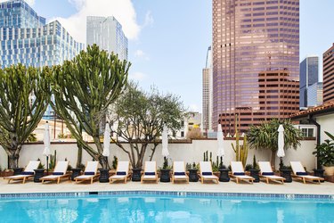 hotel pool with white chairs and city buildings in the background