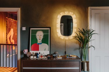 walnut console with abstract artwork and lit mirror