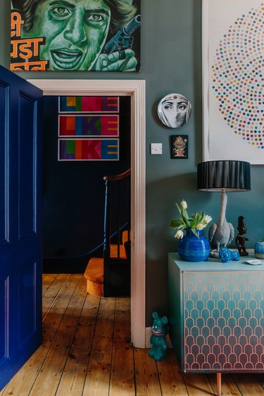 green living room going into dark blue hallway with artwork