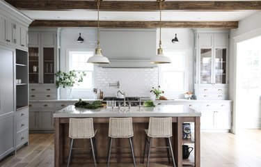 concrete and wood rustic kitchen island in kitchen with white tile backsplash