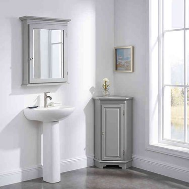 Gray corner bathroom cabinet with floating medicine cabinet and pedestal sink
