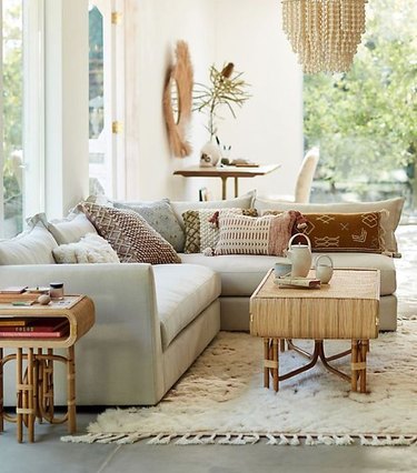 living room rug idea with an off-white flokati rug, a bamboo coffee table, and a stuffed, light-color sectoinal
