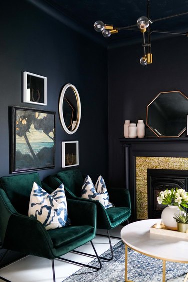 black walls in living space with green velvet chairs