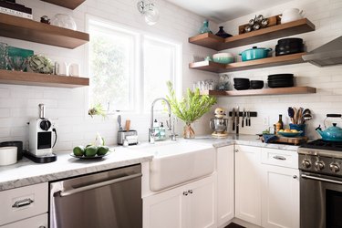 kitchen with white cabinetry, farmhouse sink, stainless steel appliances and wooden shelving units above