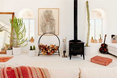 desert living room with wood burning stove and potted cacti, floor pillow seating