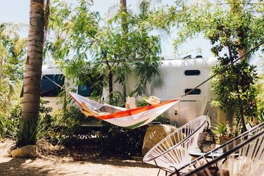 vintage Airstream with person reading in hammock and boho modern outdoor seating