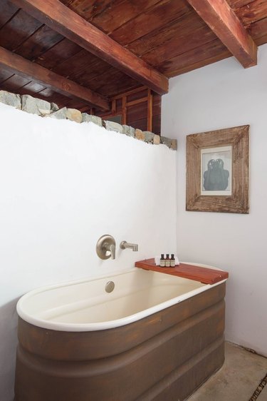 redwood open beamed ceiling in bathroom with horse trough bathtub and redwood bath caddy