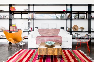 modern industrial home with bright pops of colorful furniture and contrasting bookcase