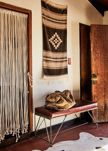 rustic entryway with leather and metal bench and Southwestern wall hanging