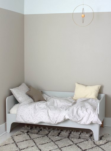 taupe minimalist girl bedroom with gold mobile and star pillow