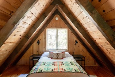 mountain A-frame cabin loft bedroom with matte black nightstands and wall sconces