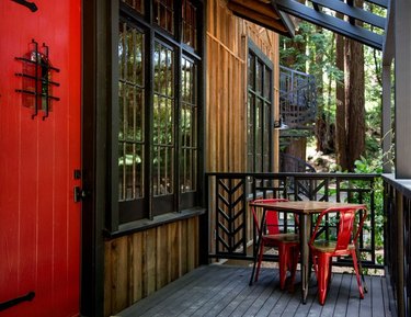 restored cabin facade with red door and small bistro table and chair set