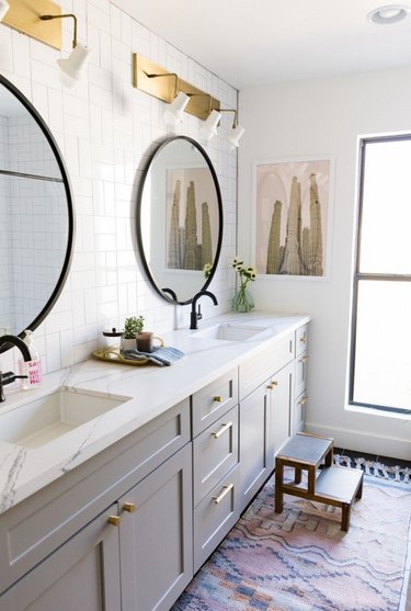 double sink bathroom lighting idea with trio of brass wall sconces above each mirror