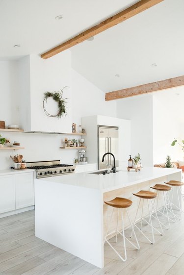 white kitchens with wood floors, exposed wood beams, and wood bar stools