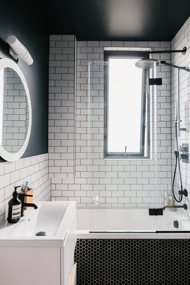 bathroom shower with white subway tile, window and white sink