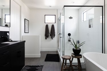 black and white bathroom with large shower, black bathroom sink and standing tub
