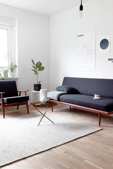 minimalist lighting in living room with dark gray futon and neutral rug