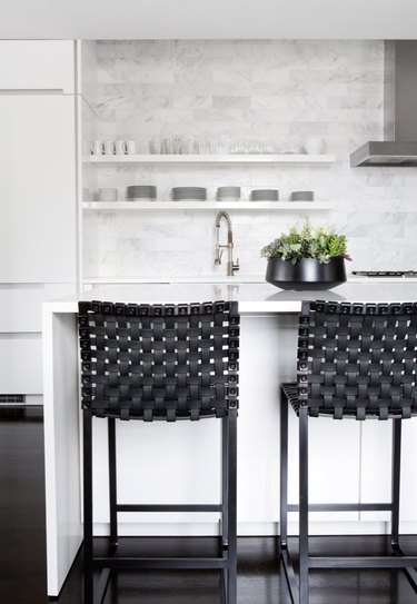 white kitchens with wood floors, black bar stools, and stainless steel hood