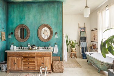 unique bathroom layout with wood sink vanity and white countertop, turquoise accent wall, and antique clawfoot tub