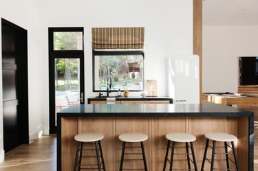 Waterfall kitchen island with black counter, light wood base.