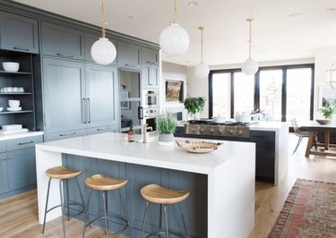 Two waterfall kitchen islands with white counters, gray cabinets, and white pendant lights.