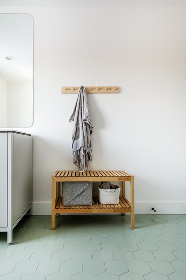 teak wood bench with minimalist bathroom storage and green hex tile