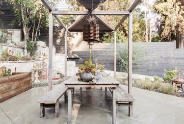 Outdoor dining set with modern pergola and concrete patio.