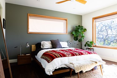 Bedroom with green wall, colorful red blanket on white duvet cover