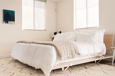 Wood bed frame with white bedspread in California modern bedroom