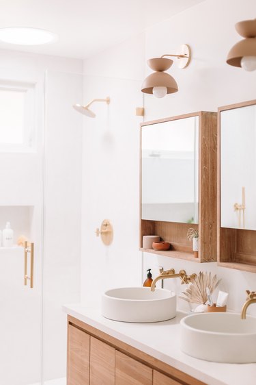 white bathroom with glass shower door and minimalist bathroom storage