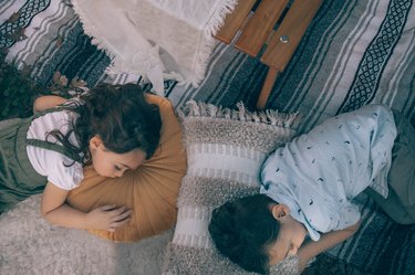 Two kids sleeping on pillows in glamping site