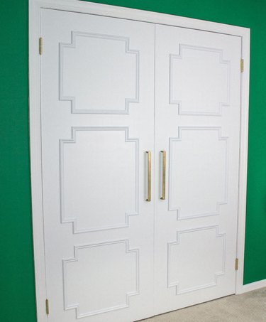 Art deco DIY project with white closet doors featuring molding and bright green wall