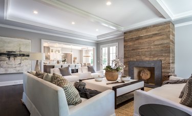 transitional family room with reclaimed wood fireplace, white sectional, side chairs and sofas.