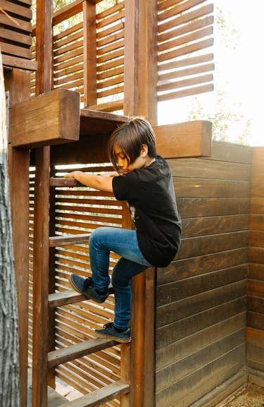 Boy descending modern treehouse ladder