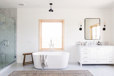 open concept bathroom with shower with glass wall, stand-alone tub in front of window and single-faucet bathroom vanity