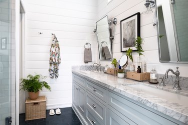 bathroom with white shiplap wall, two sink bathroom vanity, light grey cabinetry and mirrors