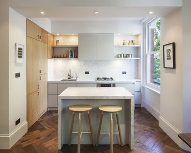 small mitred marble kitchen island in contemporary kitchen with herringbone floor