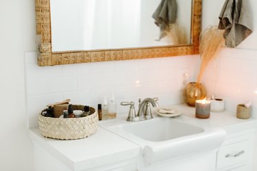 small white sink, wicker basket and lit candle