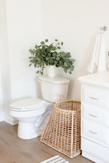 bathroom toilet, wicker basket and wood flooring