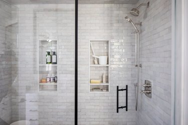 close up view of shower with subway tile walls and built-in storage