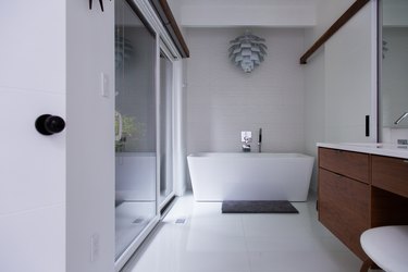 modern bathroom with shower on the left, stand-alone bathtub in the center and natural wood bathroom vanity on the right