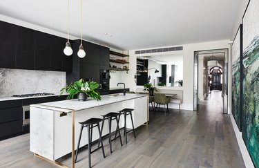 dolomite marble kitchen island with brass details in kitchen with black cabinets