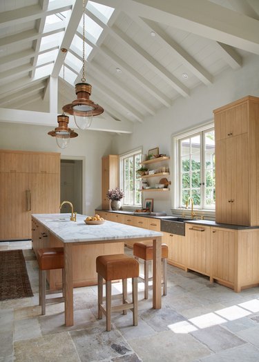 modern design with tall kitchen cabinets in light wood finish, vaulted ceiling and skylights
