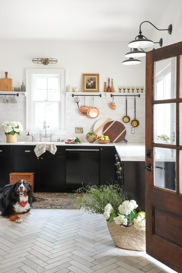 dark kitchen cabinets with light floors and hanging copper pots